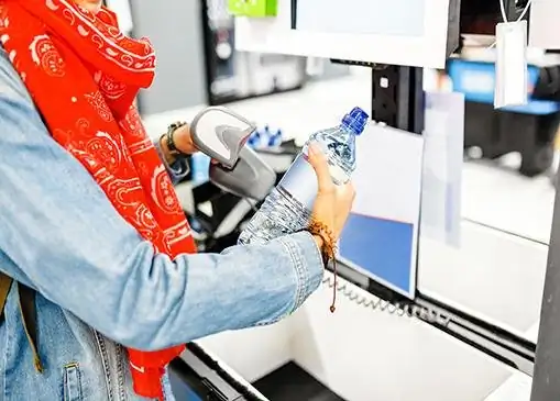 Shopper scanning a bottle of water at a retail self-checkout station