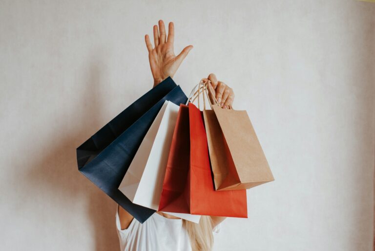 Person holding up an armful of colorful paper shopping bags
