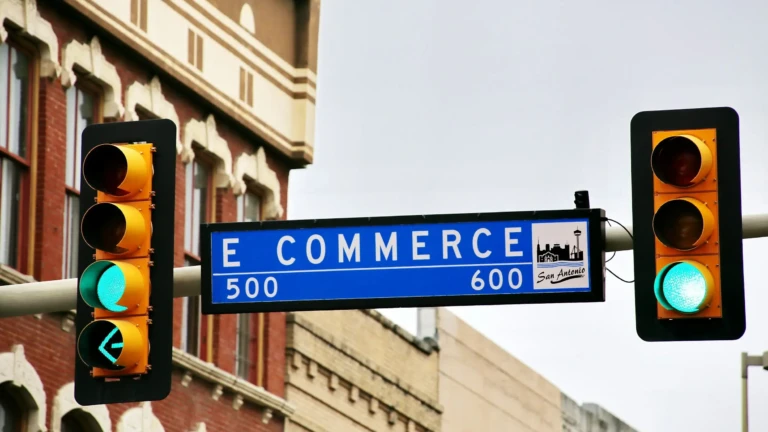 Street sign reading E Commerce between two traffic lights showing green
