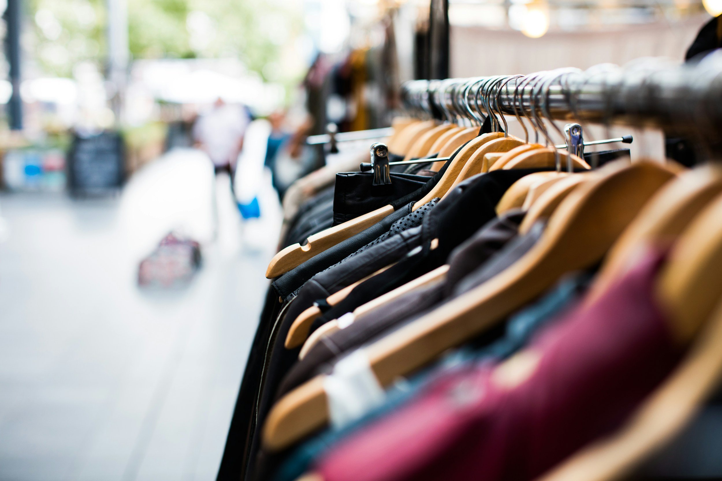 Rack of clothing on wooden hangers outside a retail shop